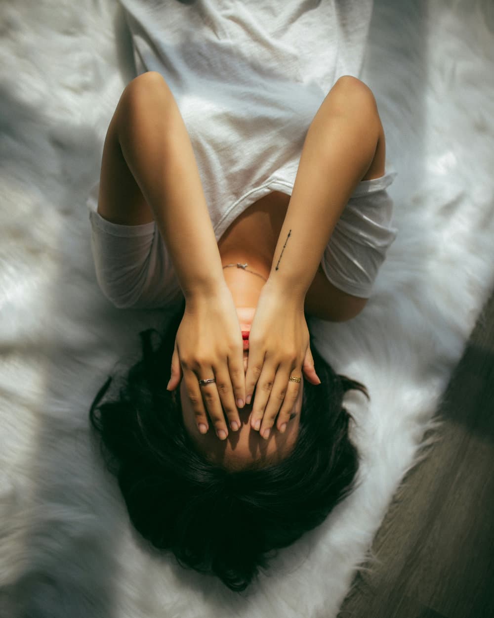A woman lying down with her hands over her face